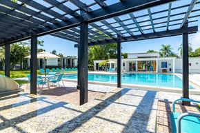 Clearwater apartment for rent - A pool area with a wooden pergola and blue chairs.