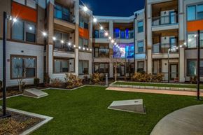 Grand Prairie apartment for rent - an apartment yard with grass and lights at night