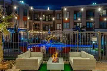 Grand Prairie apartment for rent - A pool with a fire pit in front of a building at night.