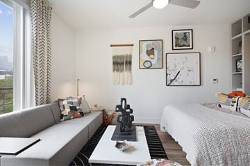 Austin apartment for rent - A living room with a grey couch and a white bed.
