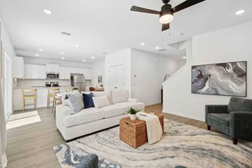 Bluffton apartment for rent - A modern living room with a white sofa and a ceiling fan.