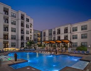 Atlanta apartment for rent - Dusk shot of pool with in-water lounge seats, additional lounge chairs, lighted fountain and covered area