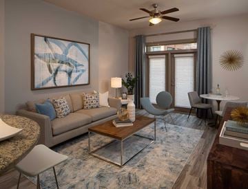Atlanta apartment for rent - A living room with a grey couch, a coffee table, a chair, a table with a vase and a painting on the wall.