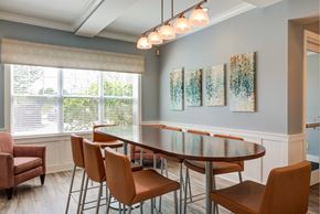 Methuen apartment for rent - Resident lounge with high-top, oval-shaped table surrounded by stools with chair backs in front of an oversized window at Summit Place apartments in Methuen, MA.