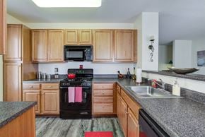 Methuen apartment for rent - Kitchen with hardwood-style flooring, honey upper and lower cabinets with ample countertop space and black oven with mounted microwave above at Summit Place apartments in Methuen, MA.