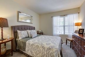 Methuen apartment for rent - Furnished bedroom with plush carpeting and oversized window with mini-blinds. Room includes queen-sized bed, two nightstands, chair, lamp and horizontal dresser. at Summit Place apartments in Methuen,