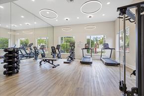 Miami apartment for rent - a gym with cardio machines and weights on a wooden floor