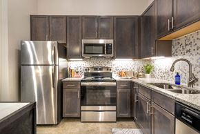 Rockwall apartment for rent - A kitchen with dark wood cabinets and stainless steel appliances.