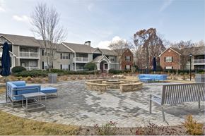Gainesville apartment for rent - an outdoor patio with a fire pit and benches in front of an apartment building