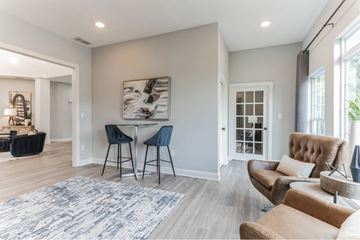 Gainesville apartment for rent - A modern living room with a dining area and a large abstract painting on the wall.