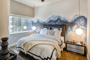 Dallas apartment for rent - A bedroom with a large bed and a mountain mural on the wall.