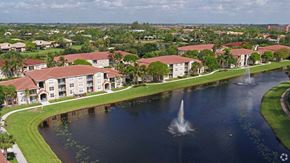 Delray Beach apartment for rent - A fountain in the middle of a lake in front of apartment buildings.