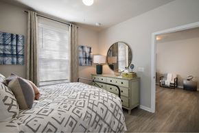 Orlando apartment for rent - A bedroom with a patterned bedspread and a dresser with a mirror.