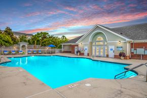 Wilmington apartment for rent - A swimming pool in front of a building with a sunset in the background.