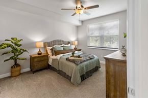 Fort Myers apartment for rent - carpeted bedroom with large window and ceiling fan and light fixture  