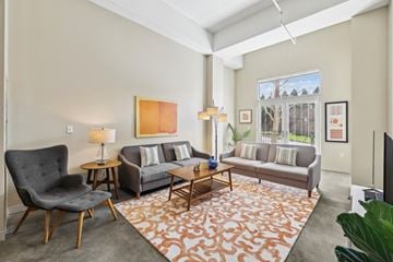 Nashville apartment for rent - A living room with a grey couch, a black chair, a wooden coffee table, and a large painting on the wall.