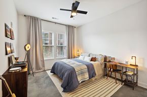 Huntsville apartment for rent - A bedroom with a bed, desk, chair, and a ceiling fan.