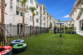 Miami apartment for rent - A playground with a swing set in the middle of a grassy area in front of apartment buildings.