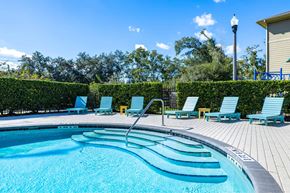 Lakeland apartment for rent - A swimming pool with blue water and lounge chairs.