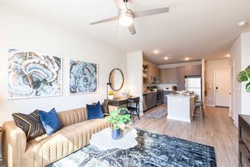 Gainesville apartment for rent - A living room with a beige couch and a ceiling fan.