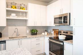 Gainesville apartment for rent - A kitchen with white cabinets and a black microwave.