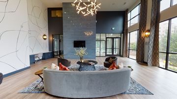 Dallas apartment for rent - A modern living room with a grey sofa and a chandelier.