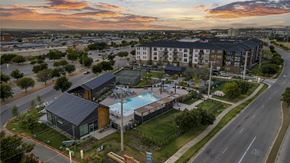 Round Rock apartment for rent - A sunset view of a road with a building and a pool.