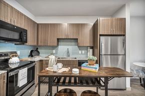 Round Rock apartment for rent - A kitchen with a black stove and wooden cabinets.