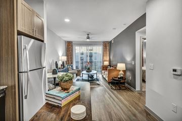 Round Rock apartment for rent - A modern kitchen with a refrigerator, a dining table with chairs, and a living area with a couch.