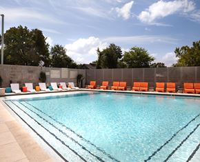 Austin apartment for rent - A swimming pool with orange chairs and a concrete wall.