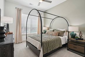 Plano apartment for rent - A bedroom with a four poster bed and a ceiling fan.