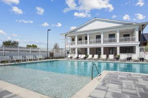 Plano apartment for rent - A pool in front of a white house with a balcony.