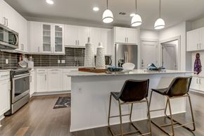 Dallas apartment for rent - A kitchen with white cabinets and a white island with two chairs.