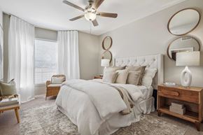 Grapevine apartment for rent - A bedroom with a large bed, a ceiling fan, and a nightstand with a lamp.