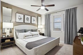 Prosper apartment for rent - A bedroom with a large bed, a ceiling fan, and a nightstand with a clock.
