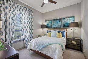 Ft. Worth apartment for rent - A bedroom with a bed, nightstand, and window with curtains.