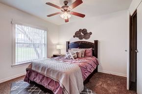 Dallas apartment for rent - A bedroom with a bed, pillows, and a ceiling fan.