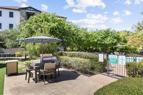 Austin apartment for rent - A patio with a table and chairs and a pool in the background.
