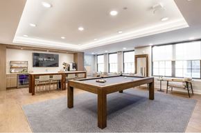 Ridgewood apartment for rent - A billiard table is in the middle of a room with a kitchen area in the background.