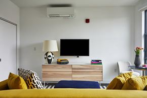Charlestown apartment for rent - A modern bedroom with a yellow bed and a television on a wooden stand.