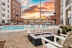Greenville apartment for rent - A sunset view of a pool area with chairs and a fire pit.