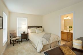 Fairfax apartment for rent - A bedroom with a large bed and a nightstand with a lamp.