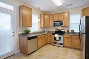Fairfax apartment for rent - A kitchen with wooden cabinets and a black refrigerator.