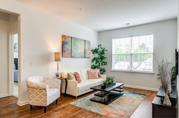 Mt. Laurel apartment for rent - A living room with a white couch, a chair, a coffee table, and a painting on the wall.