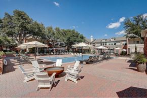 Dallas apartment for rent - a large pool with chairs and umbrellas and a building in the background