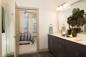 Austin apartment for rent - A bathroom with a mirror, sink, and a bedroom with a bed and window.