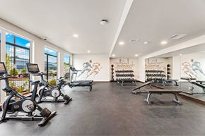 Arlington apartment for rent - A gym with a row of stationary bikes and a row of dumbbells.