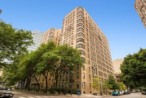 Chicago apartment for rent - A tall brown building with many windows is surrounded by trees.