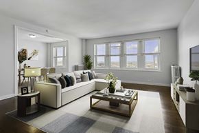 Chicago apartment for rent - A living room with a large couch, a coffee table, and a window with a view of the beach.