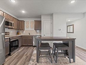 Spring Hill apartment for rent - Spring Hill, KS Apartments for Rent - Oak Woods - Kitchen with Plank Flooring, Area Rug, Moveable Island with Stool Seats, Stainless-Steel Appliances, Granite Countertops, and Espresso Cabinetry.